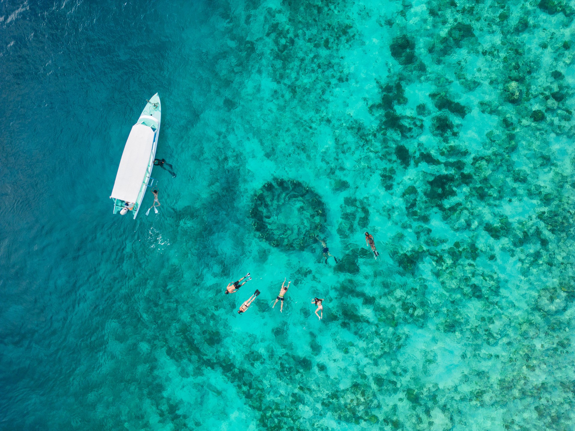 Aerial view of people snorkeling near underwater statues on Gili Meno